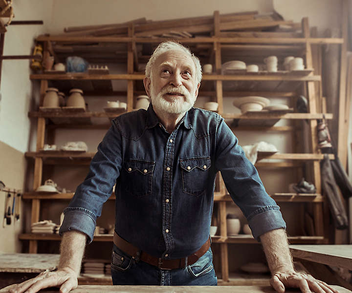 Elderly man smiling in a pottery studio.