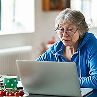 Caucasian woman in her 50s concentrating, peering at screen, working on home finances, planning for retirement