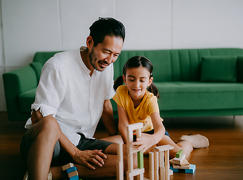 A dad playing with blocks with his daughter