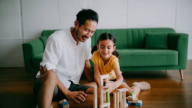 A father playing with wooden block with his daughter