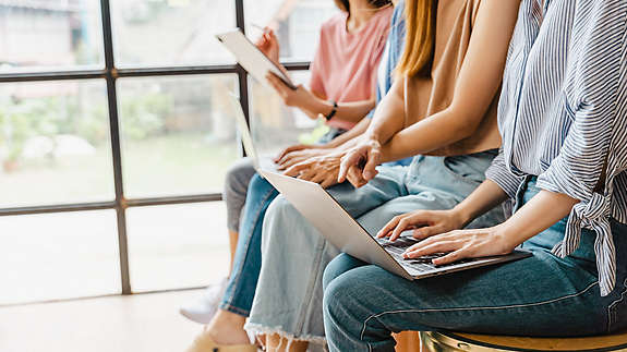People sitting down in chairs looking at their laptops and tablets