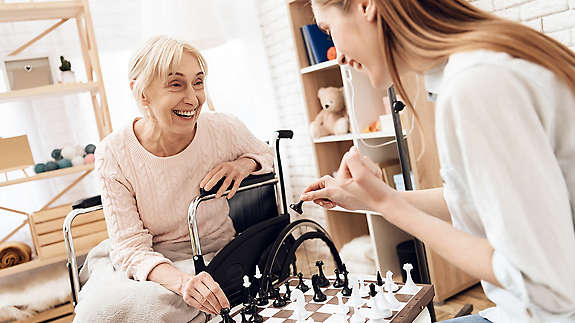 Women playing chess with older women