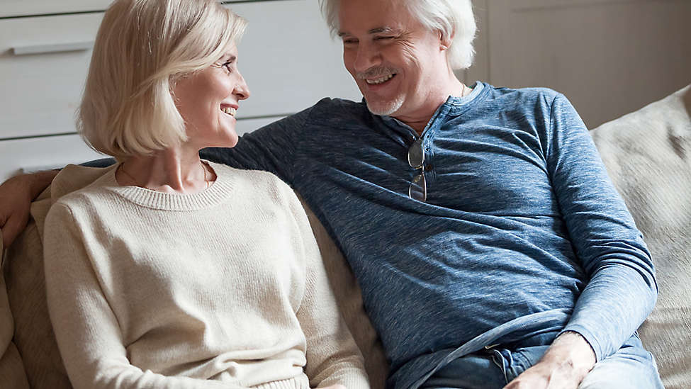 Elderly couple on couch smiling