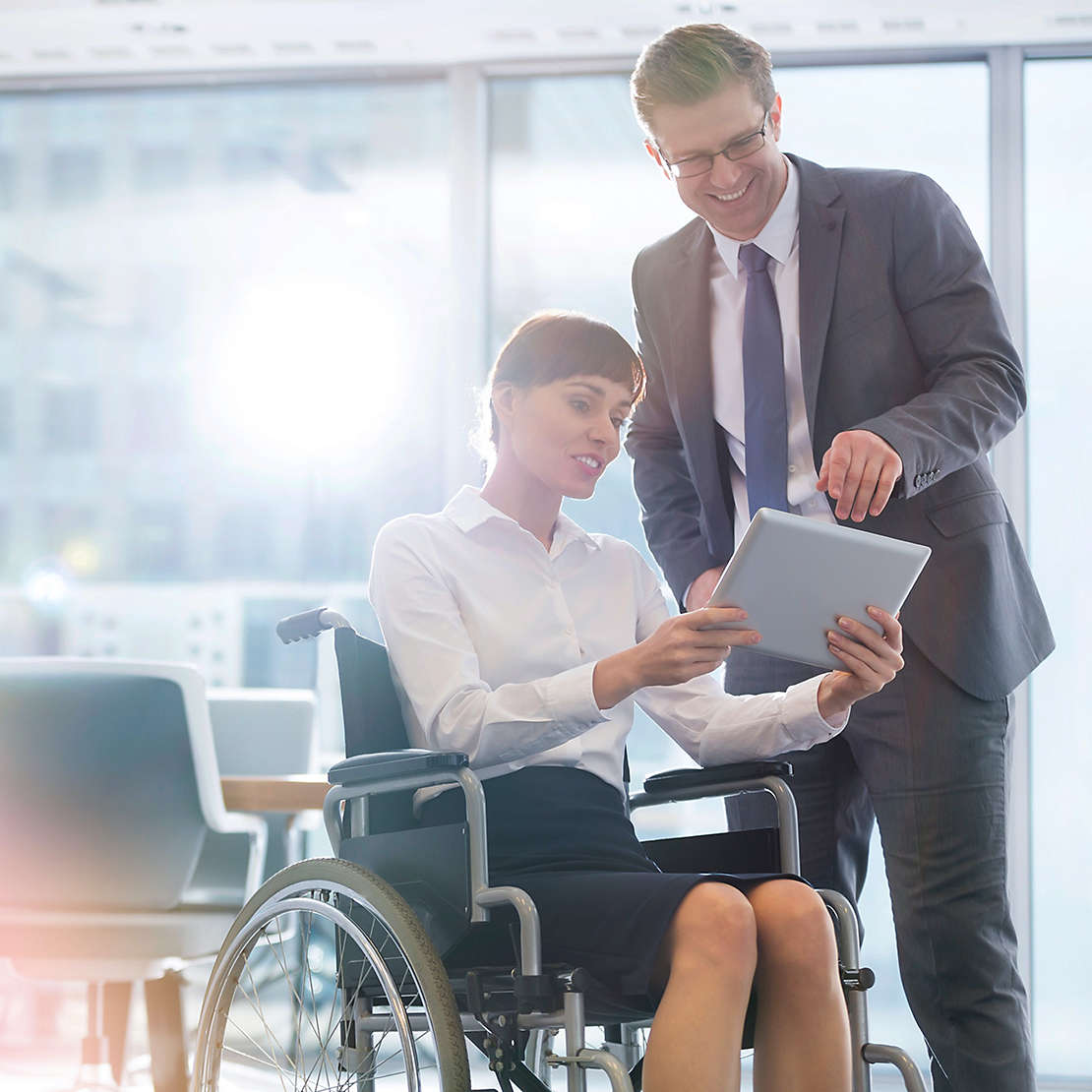 Woman in wheelchair showing a man a document on a tablet.