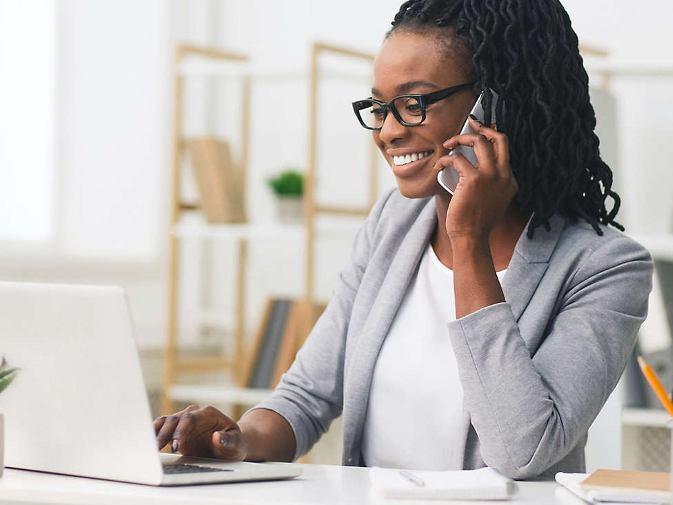 Person talking on phone while working on computer