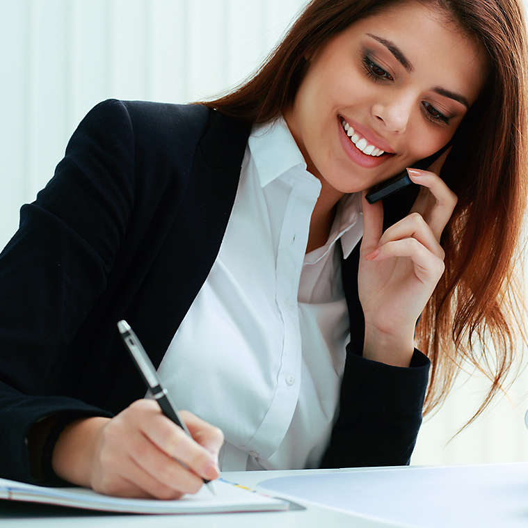Person on the phone while writing in notebook.