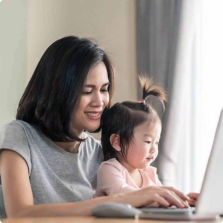 Woman working on a laptop with her child in her lap.