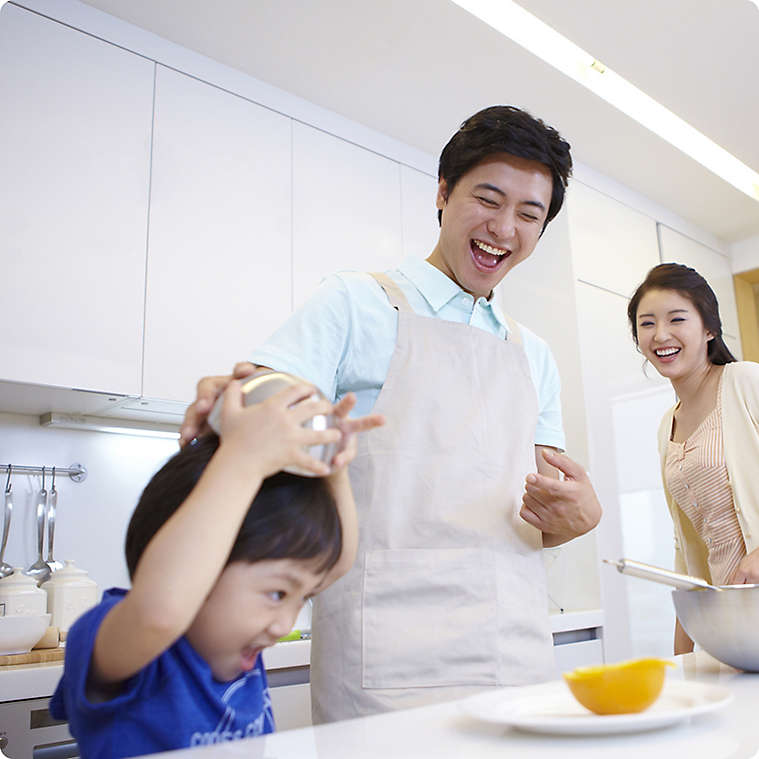 Korean family cooking in kitchen with young son
