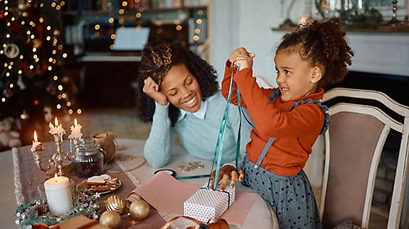 A woman with her daughter wrapping gifts