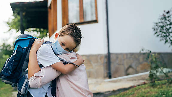 A kid wearing a mask hugging his parent