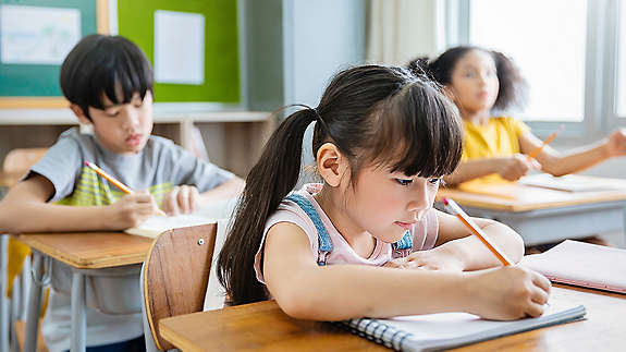 Kids writing in a notebook at school