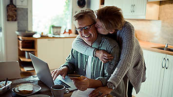 Mature couple doing online shopping and hugging