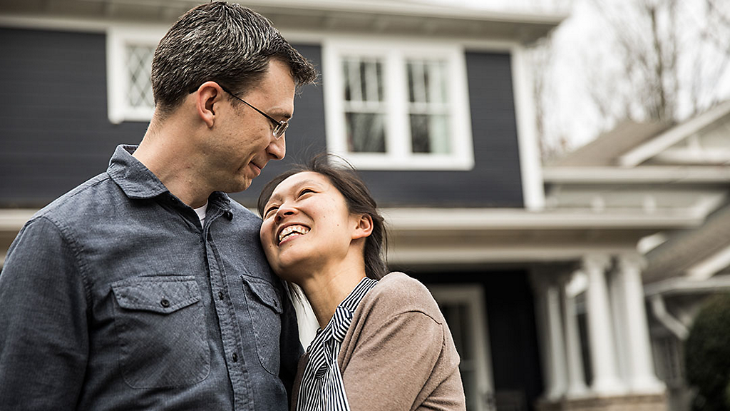 Couple hugging in front of house