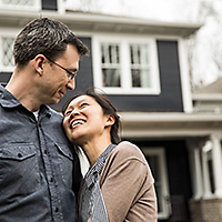 Couple hugging in front of house