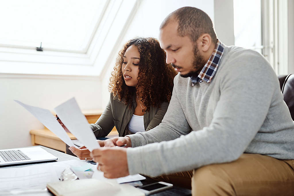 Two people sitting on a couch reviewing paperwork.