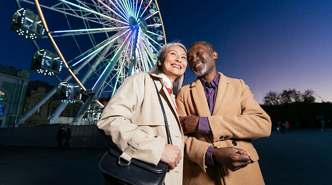 multiethnic senior couple with Ferris wheel in background 