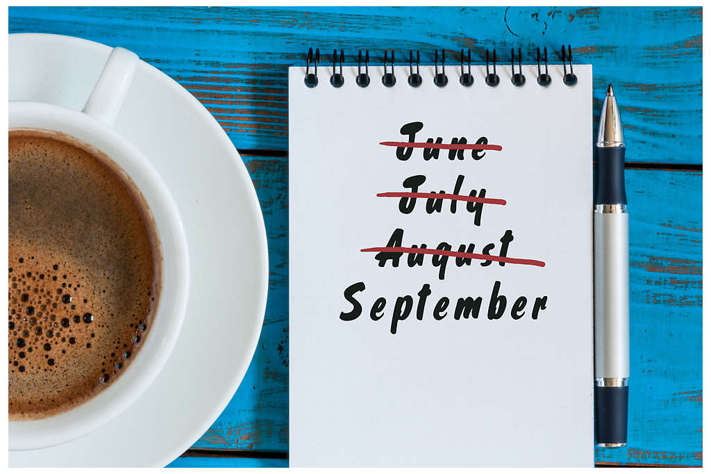 cup of coffee with notepad showing the names of summer months