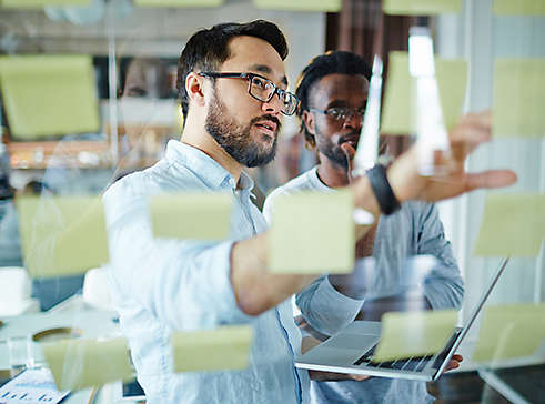 Two employees talking about different ideas on post-its.