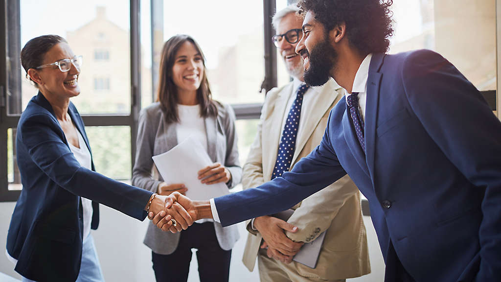 Colleagues greeting one another at work by shaking hands