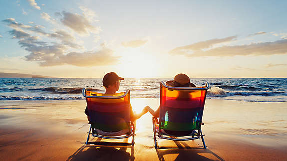 A couple sitting in beach chairs on the beach looking out towards the ocean