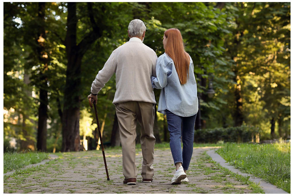 A woman helping an eldery man walk