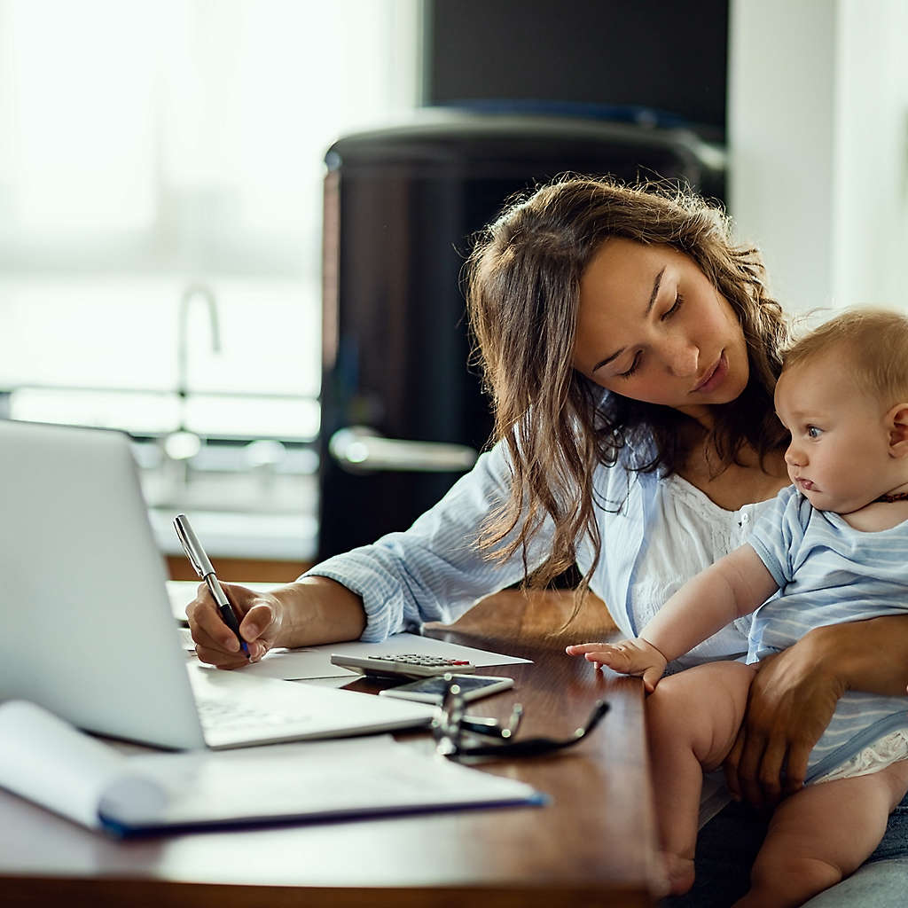mother working at a desk with a baby on her lap
