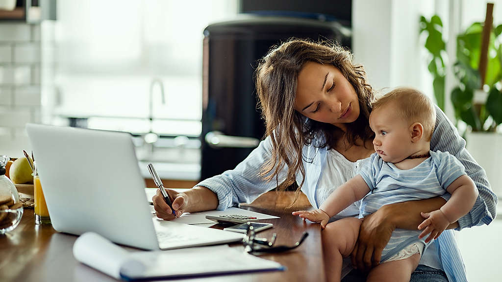 mother working at a desk with a baby on her lap