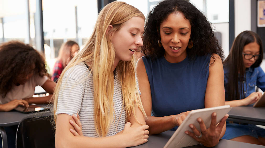 mentor helps teenage schoolgirl with tablet computer