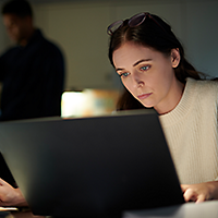 Woman working late on laptop and taking notes