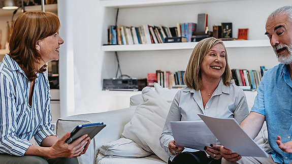 A mature couple at home discussing paperwork with an agent.