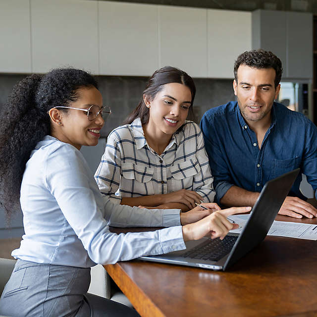 agent working with a couple point at laptop