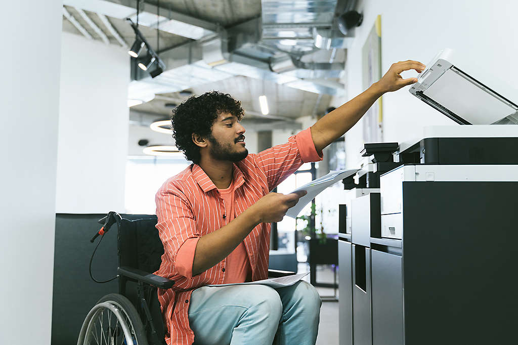 An employee with a disability looking at paperwork or shown at work
