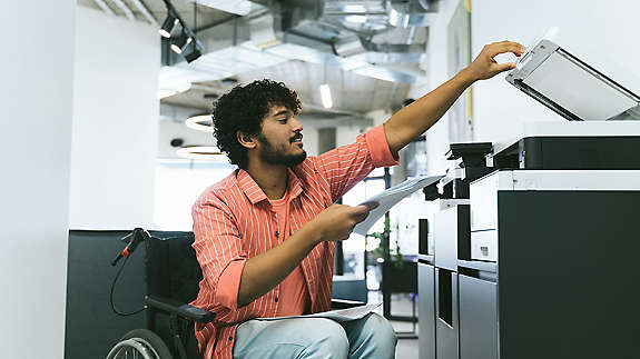 An employee with a disability looking at paperwork or shown at work