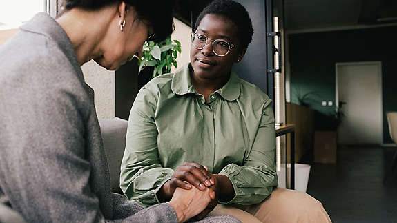 A supportive manager sitting with an employee who looks to be struggling