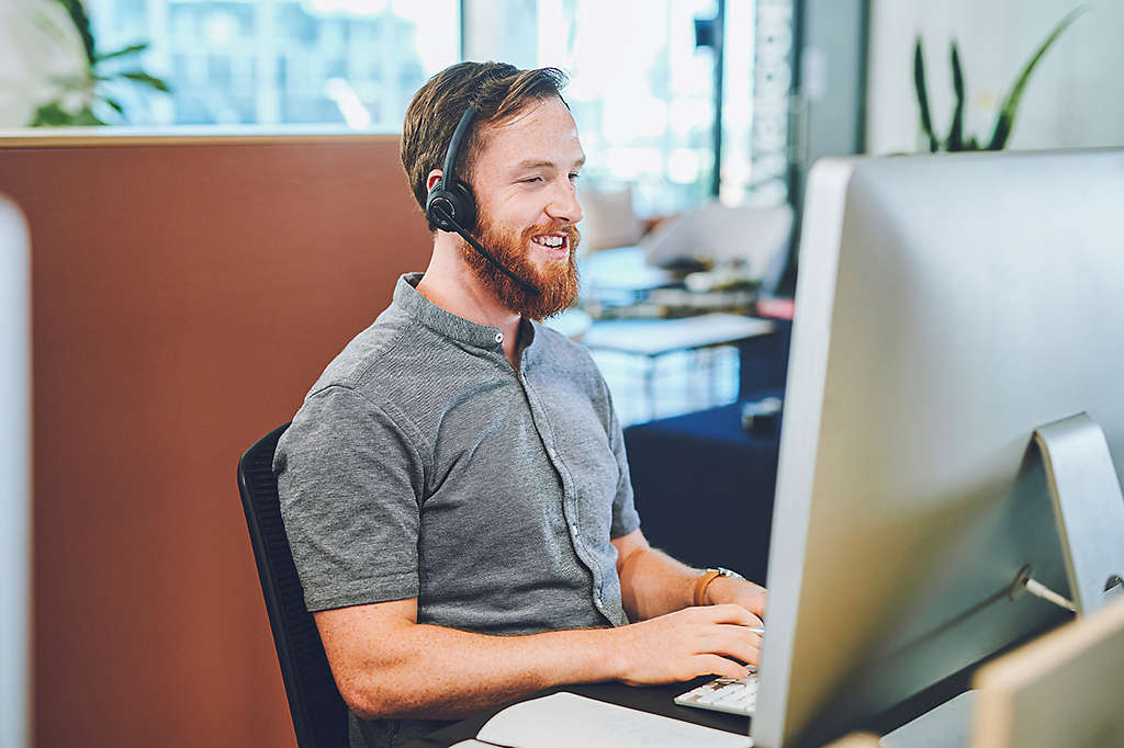 A service employee sitting at a computer helping someone