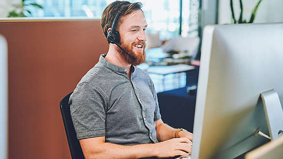 A service employee sitting at a computer helping someone