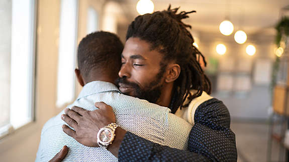A not-too-sad photo of an employee comforting one of their peers, embodying a “culture of care”
