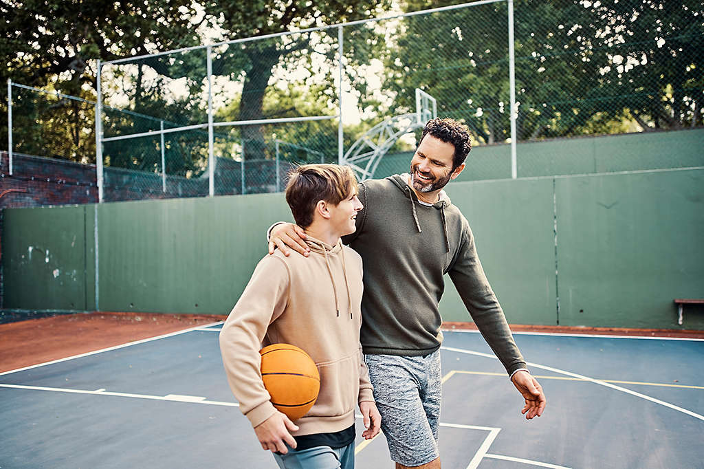 Happy father and son walking off court after playing a game of basketball