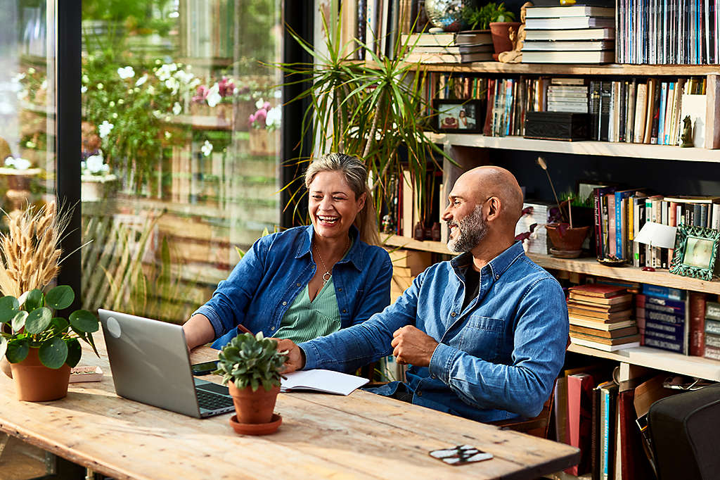 happy retired couple reviewing something on their laptop computer at home