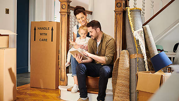 A young family sitting on the stairs of their new house.