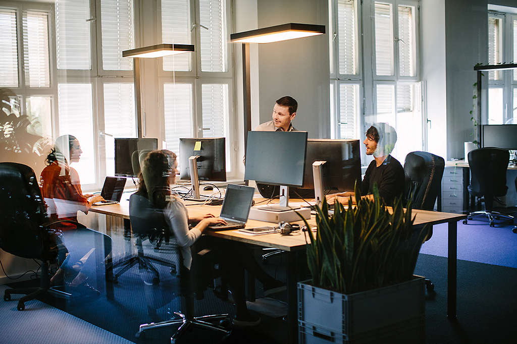 A large room with multiple workers on computer screens