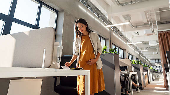 A pregnant employee in a stock room sorting boxes or other work environment 