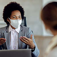 An agent wearing a mask talking with a client.