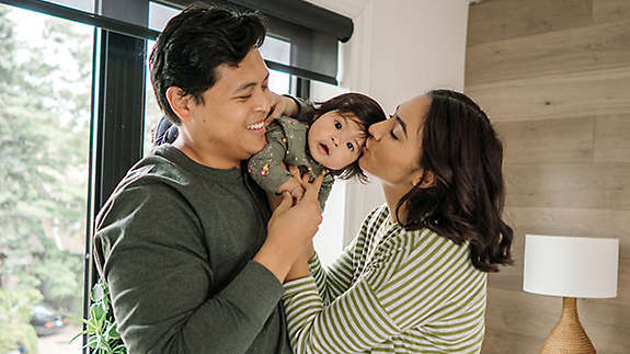 A young couple playing with their baby.