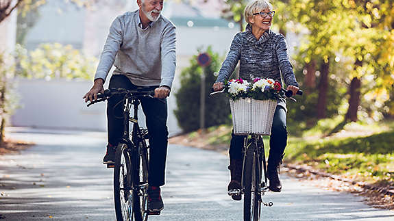 A mature couple riding bikes in the park.