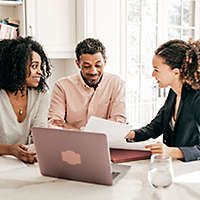 A couple sitting at a table looking at paperwork and talking to an agent.