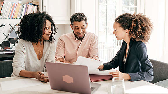 A couple sitting at a table looking at paperwork and talking to an agent.