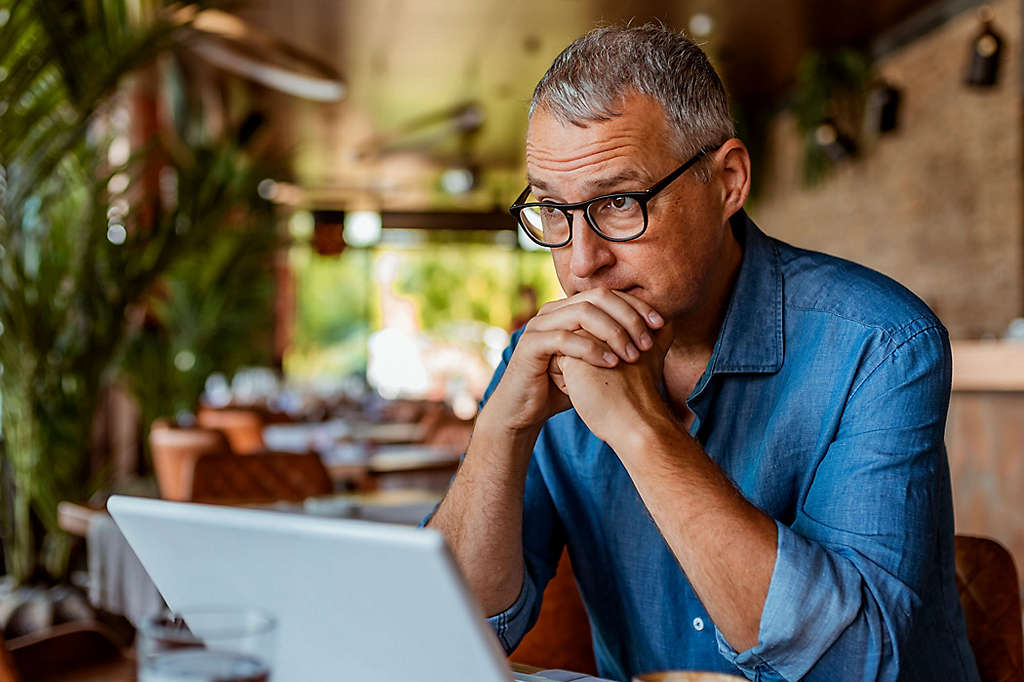 A man pondering something while sitting at his computer.