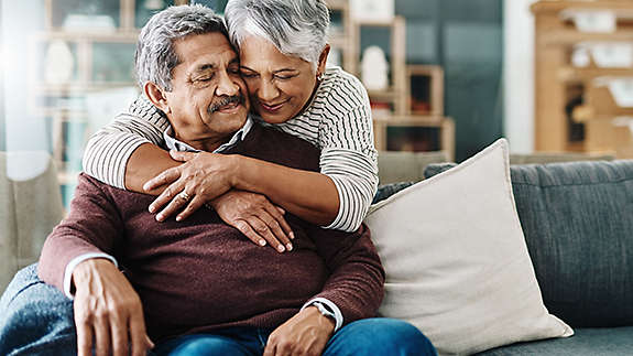 A mature woman hugging her husband from behind.