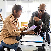 retired happy couple looking over finances on a laptop